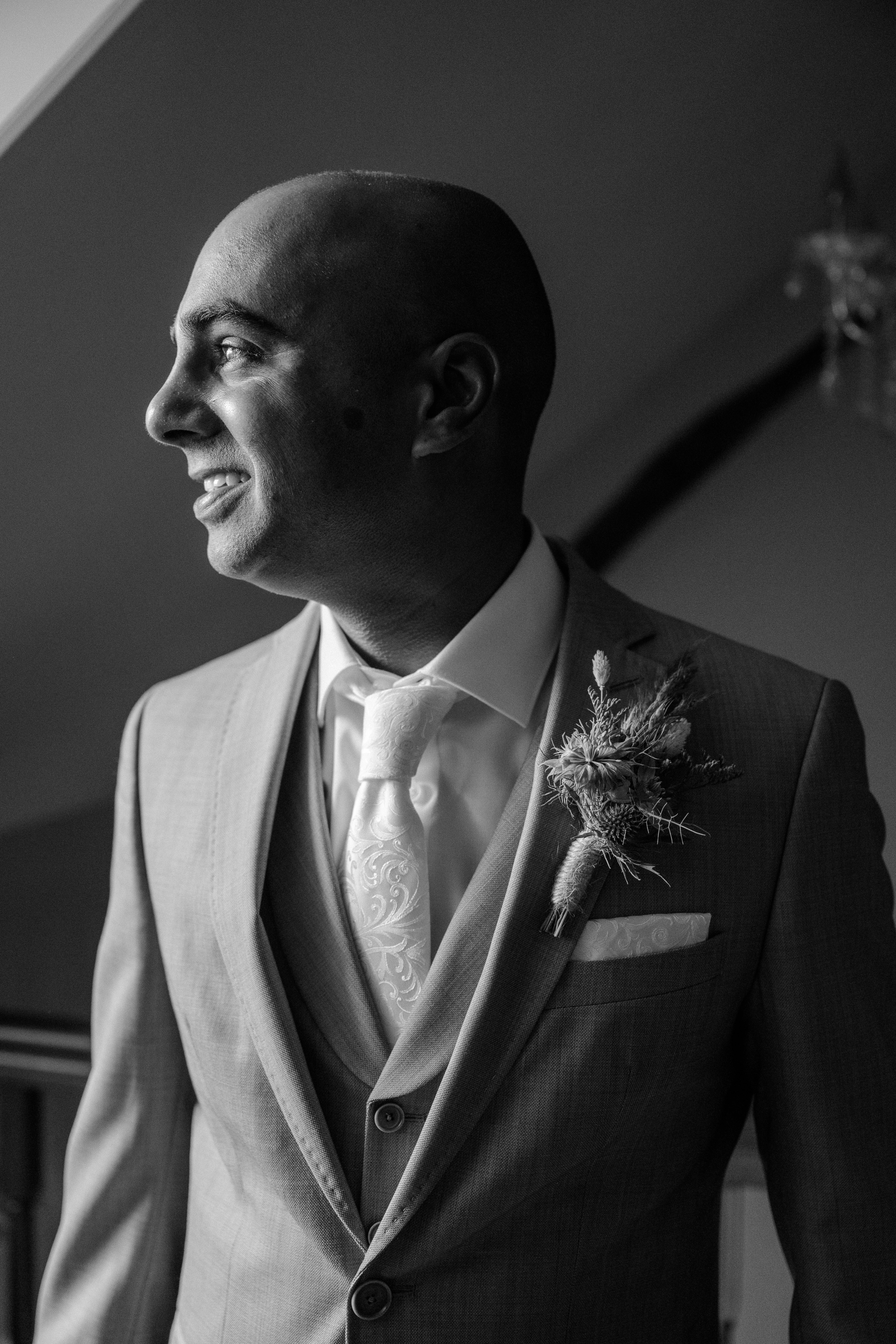 Black and white profile picture of a groom in a beige suit looking to the left
