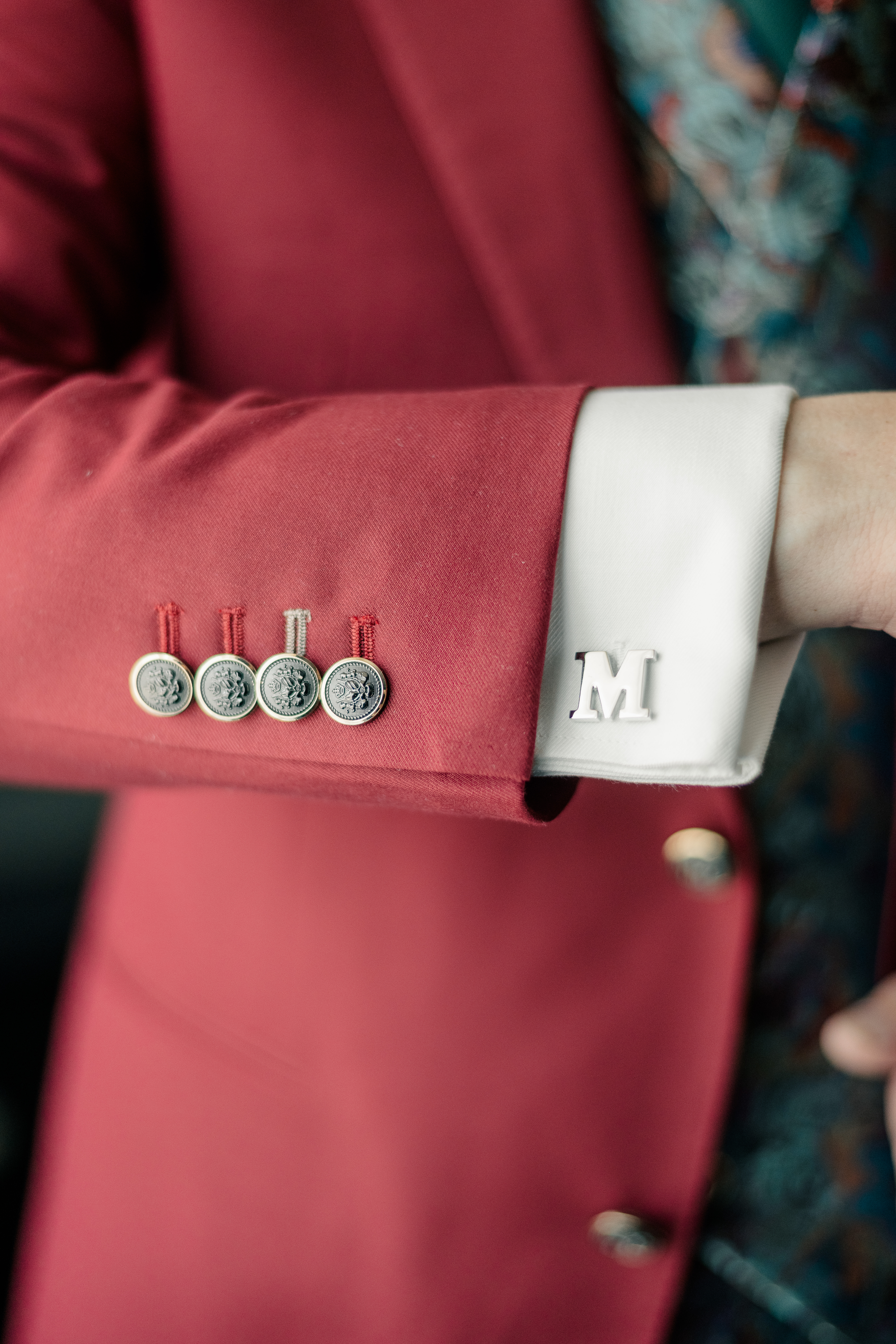 detail of embroidered button holes and letter M cufflink on groom's right arm