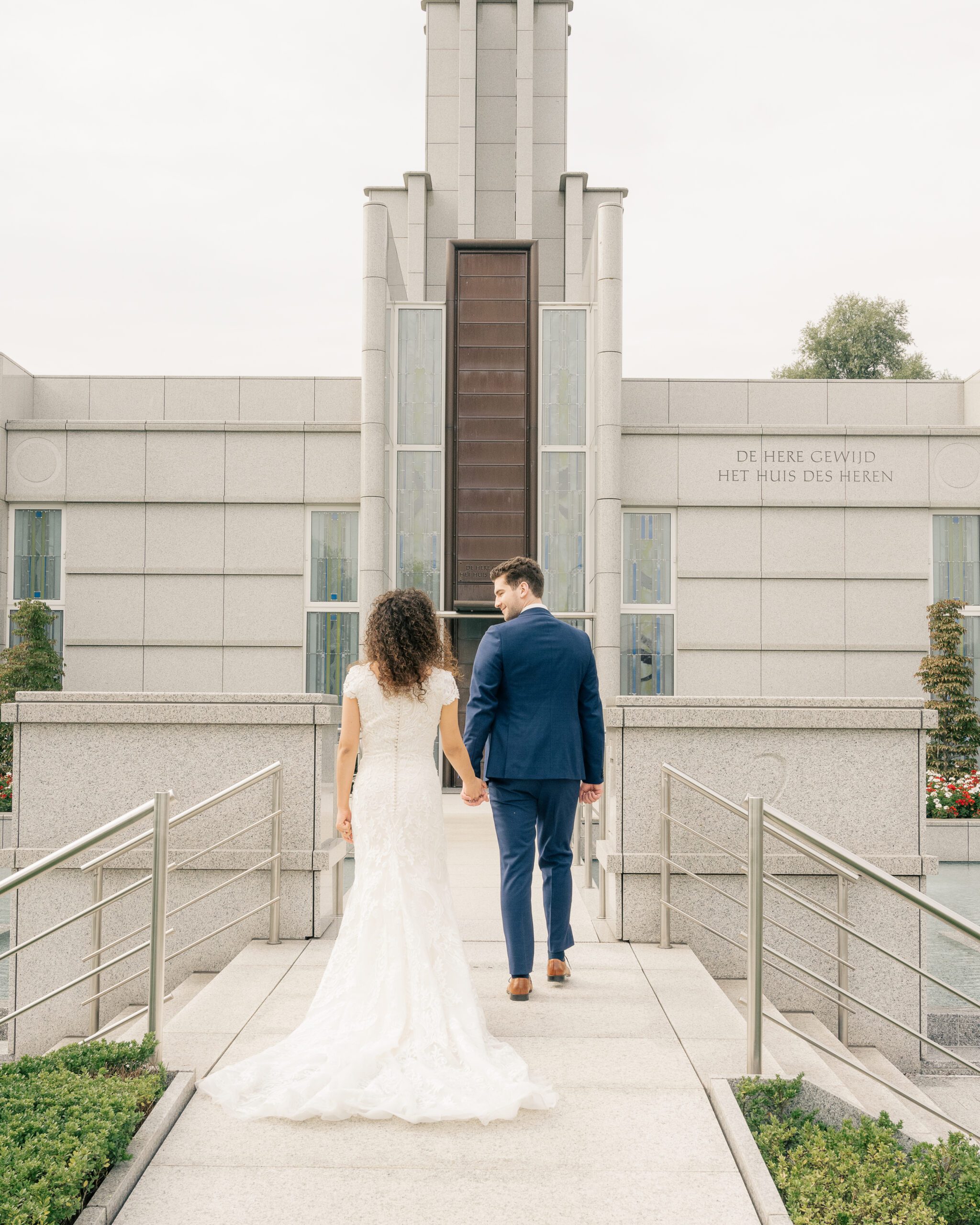 A bride and groom walk up the path to the Hague Netherlands Temple after their temple sealing