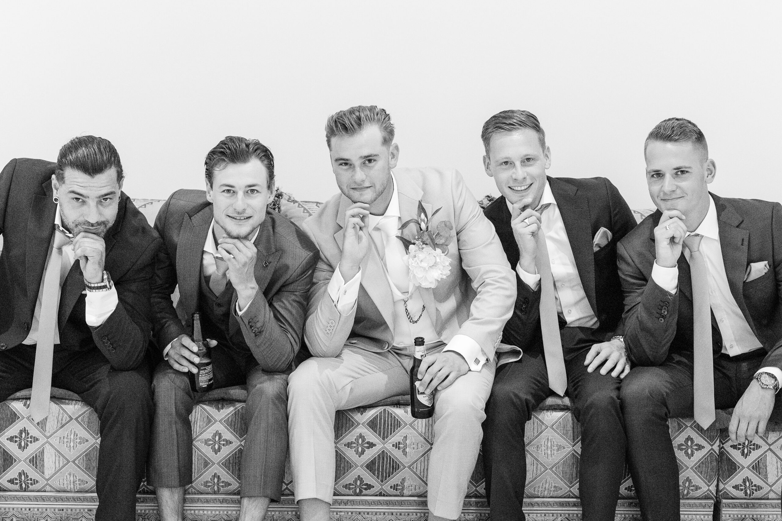 Black and white photo of groom and his four groomsmen sitting on a sofa at Mamounia palace before the wedding ceremony