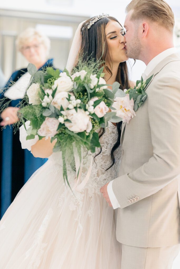 Wedding photo of bride wearing Randy Fenoli Candi dress meeting and kissing groom at altar
