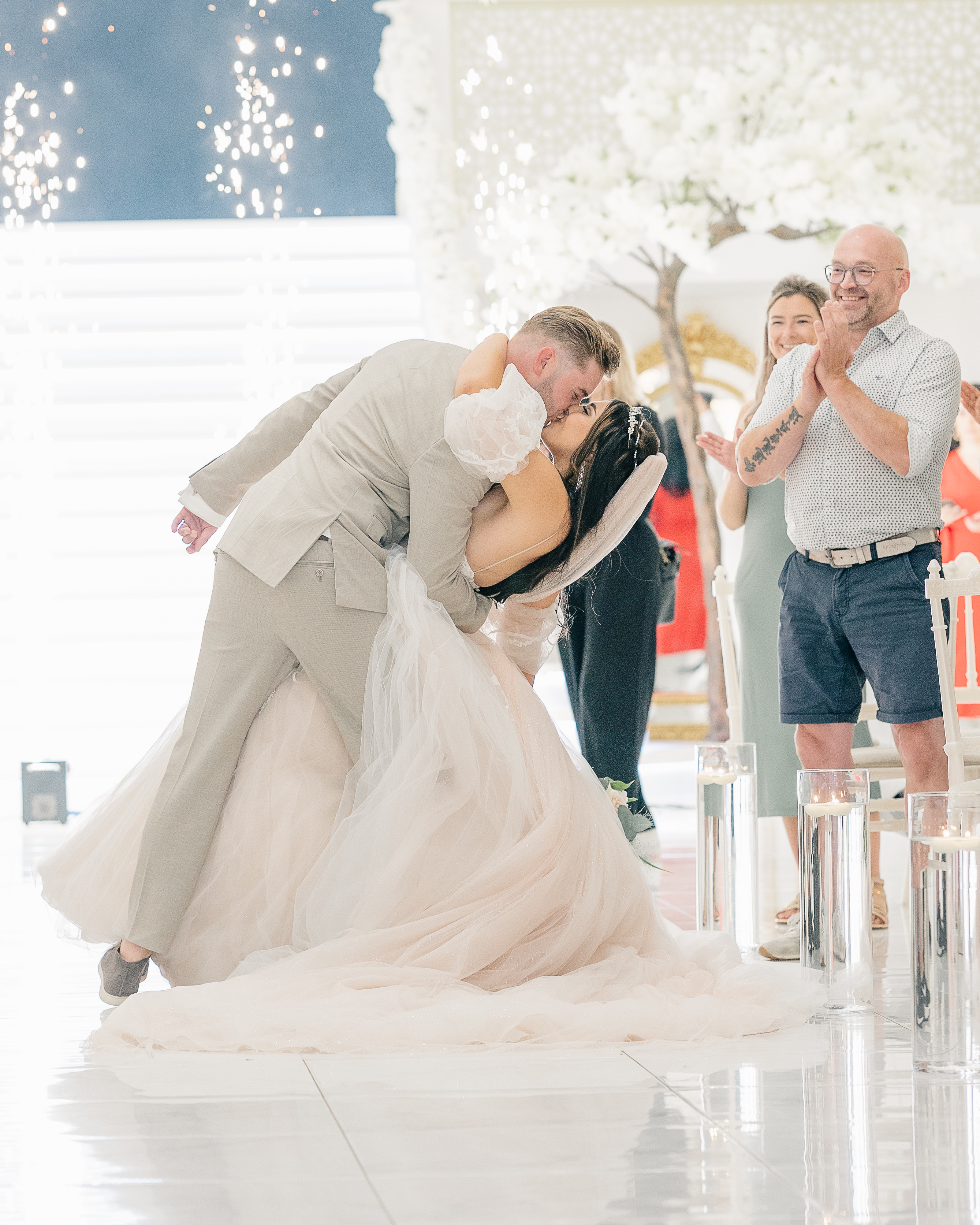 Recessional photo of groom dipping and kissing bride with fireworks
