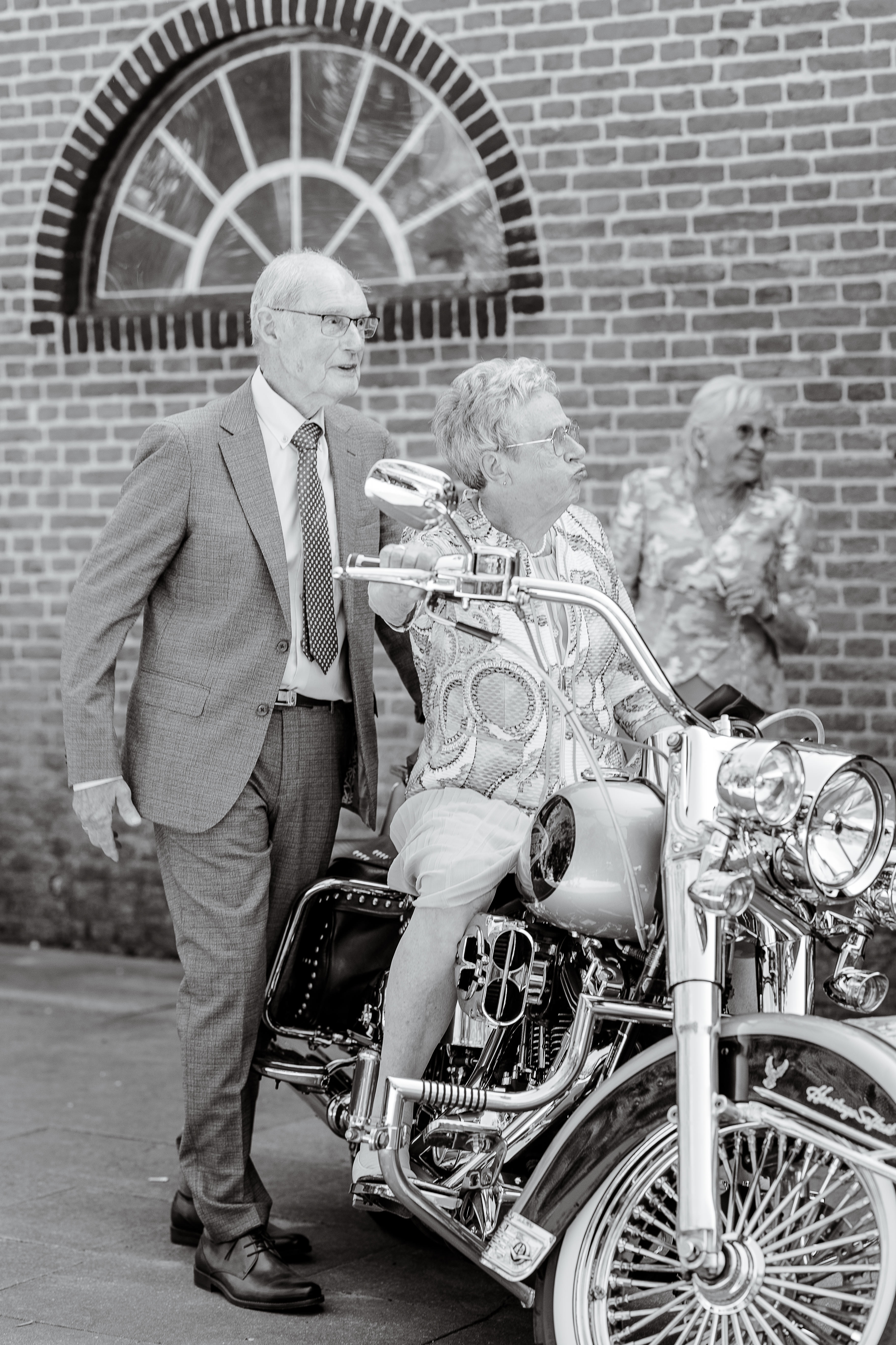 Wedding photo of wedding couple's grandparents playing with the harley davidson motorcycle during couples portraits