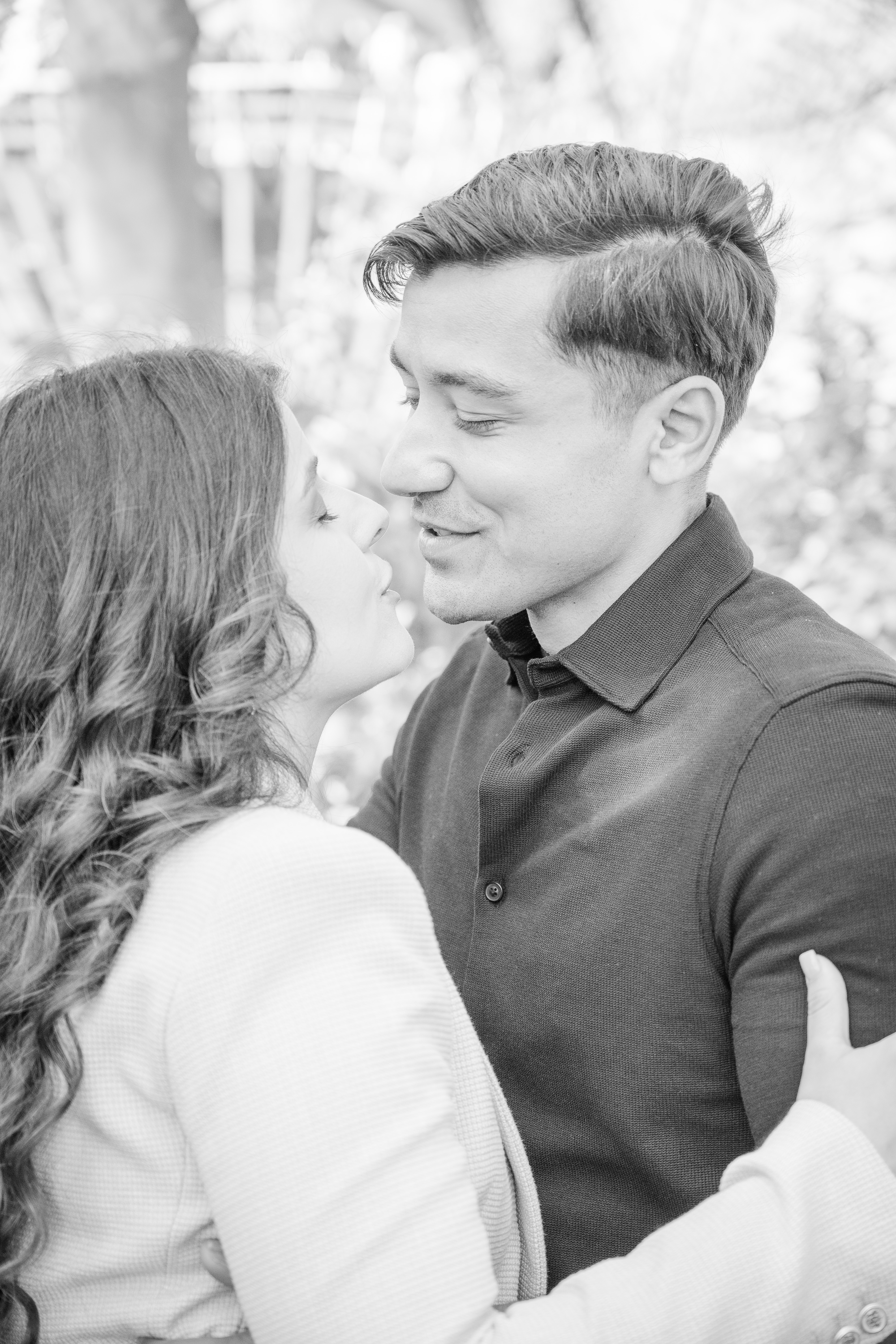 Black and white image of a husband and wife about to kiss in a garden
