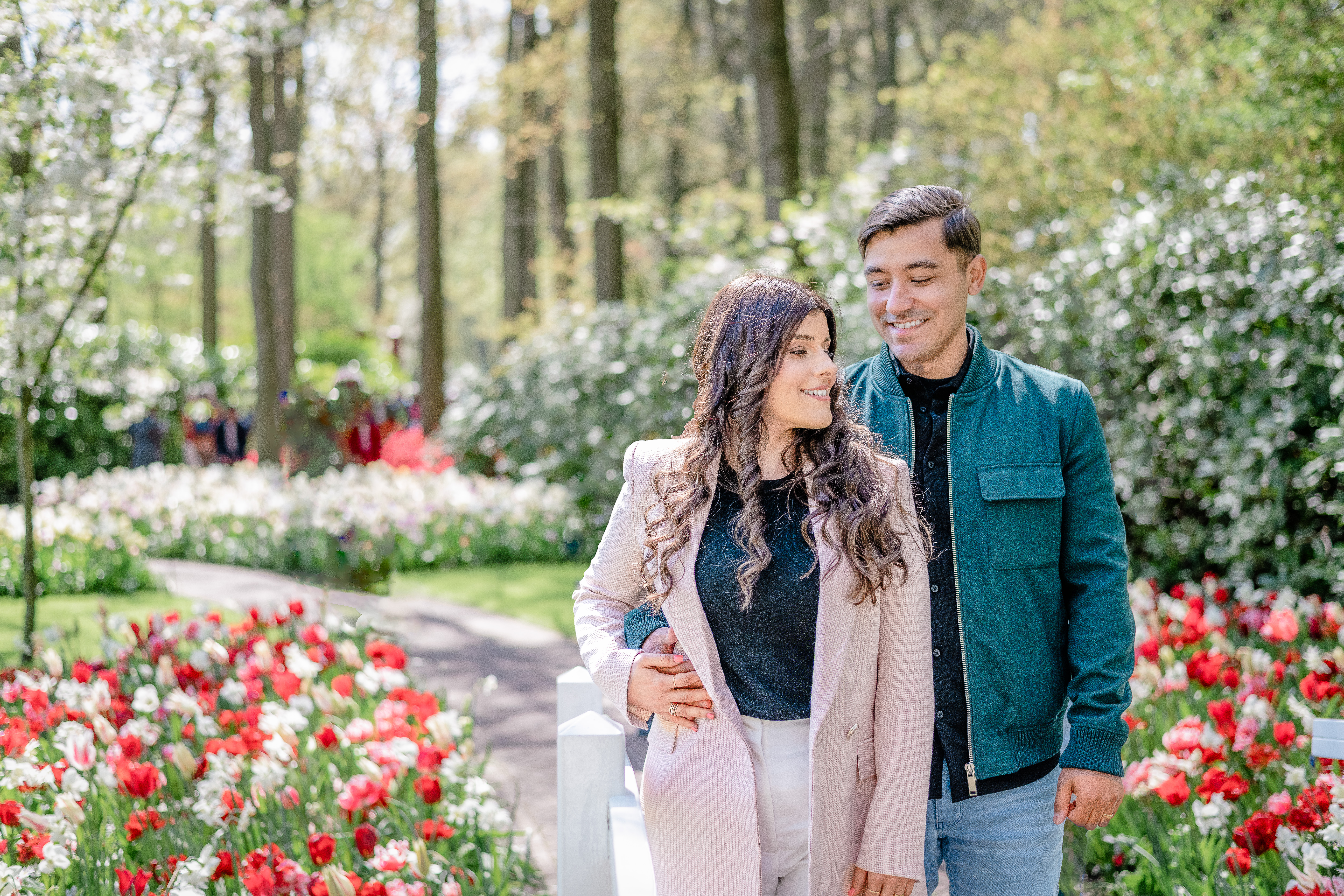 Anniversary photoshoot of husband and wife looking at each other strolling through the keukenhof garden full of blooming tulips