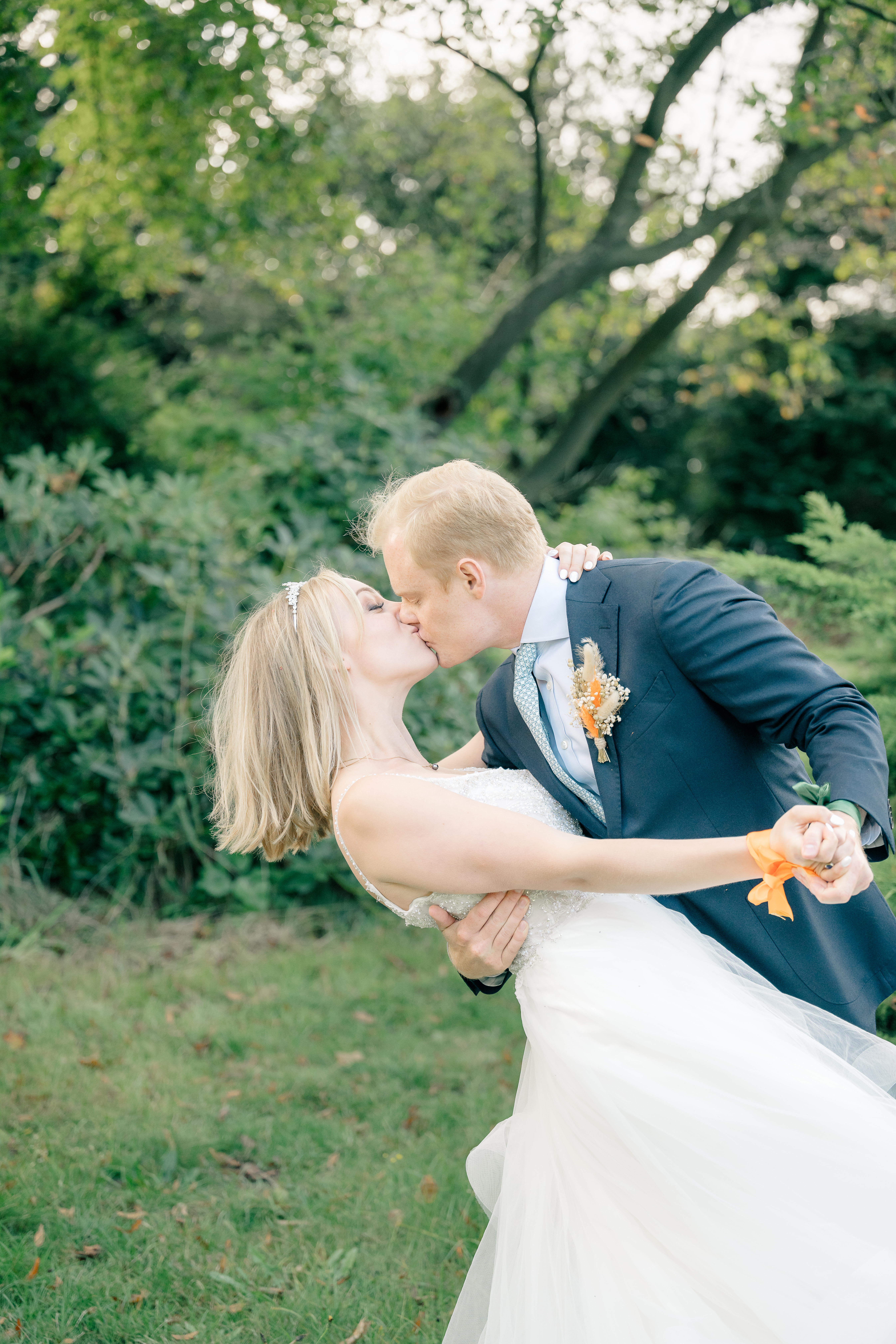 Bridal couple portrait with groom dipping and kissing bride in a garden wedding