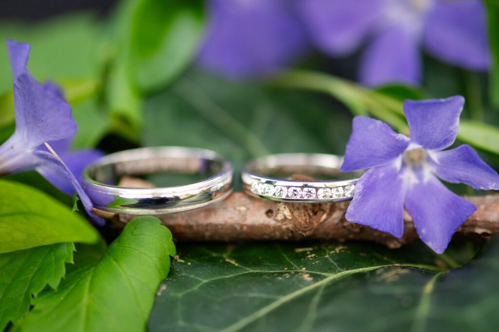 Wedding rings side by side on a stick with wildflower and ivy details around