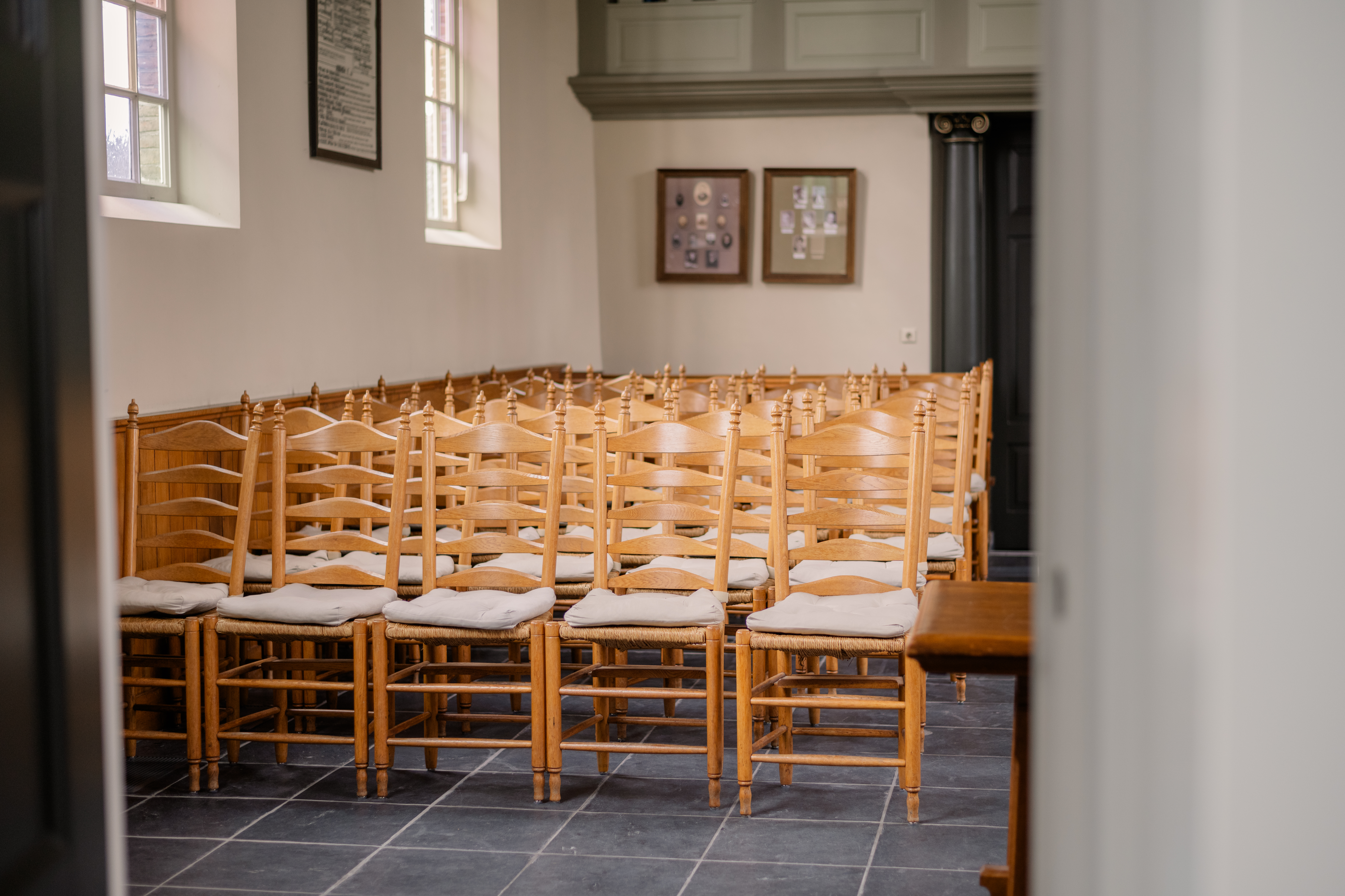View from the kitchen into the Church Hall full of wooden chairs and pews