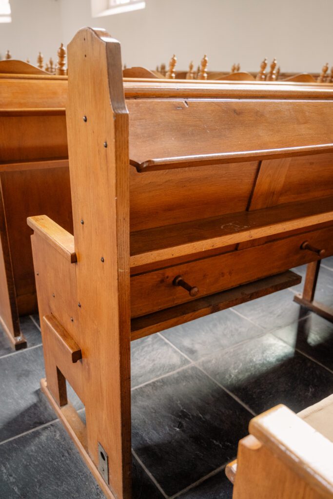 wooden pews stand on black stone floors in the chapel