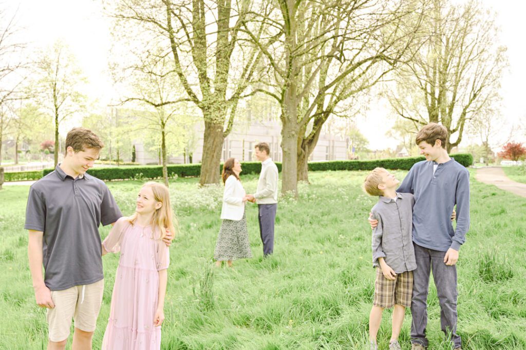 an expat family of six stands in groups in front of trees and The  Hague Netherlands temple
