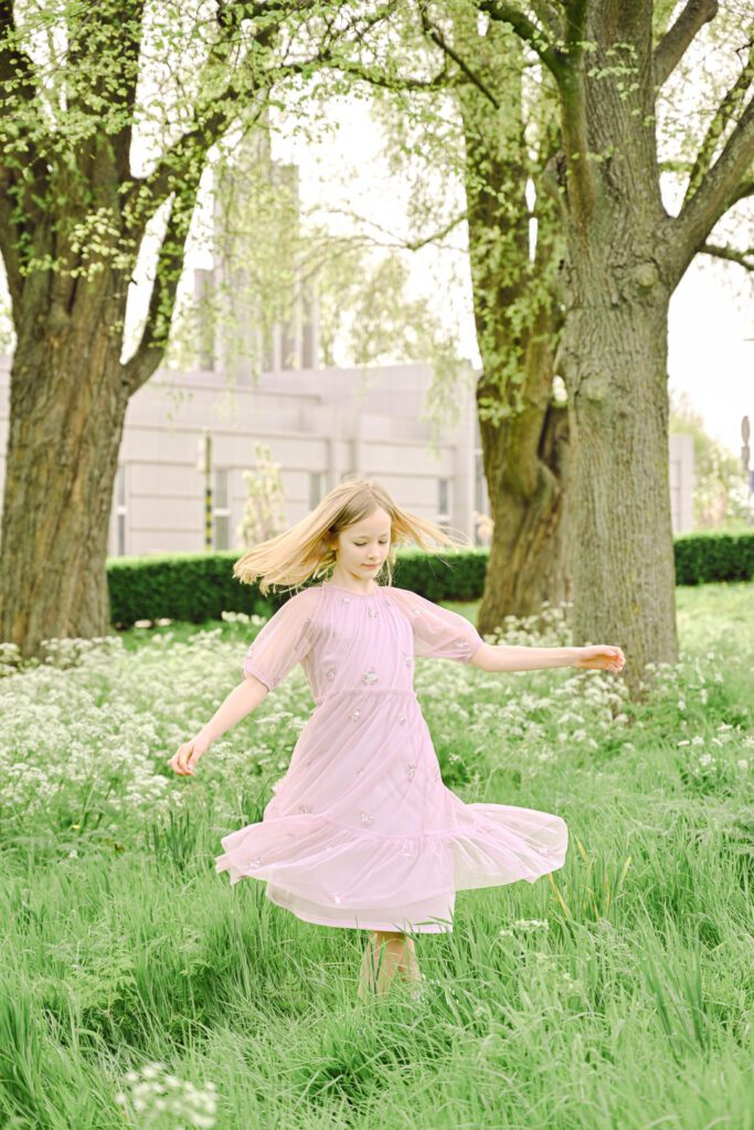 a young girl twirls in a light pink dress with The Hague Netherlands temple in the background