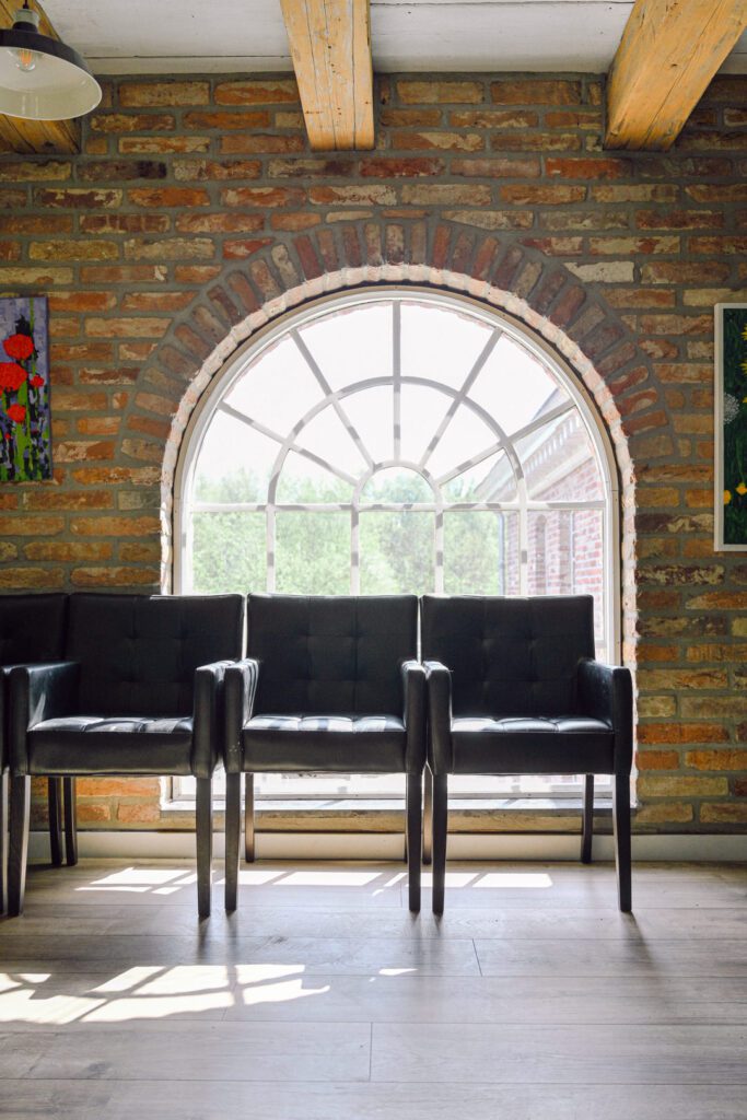 three black chairs stand in front of an arched window letting light and views of greenery in