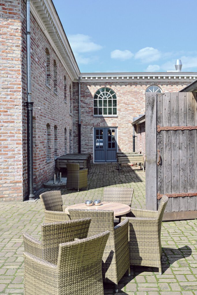 The back terrace with its arched windows and barn doors set in brick facade with a blue sky