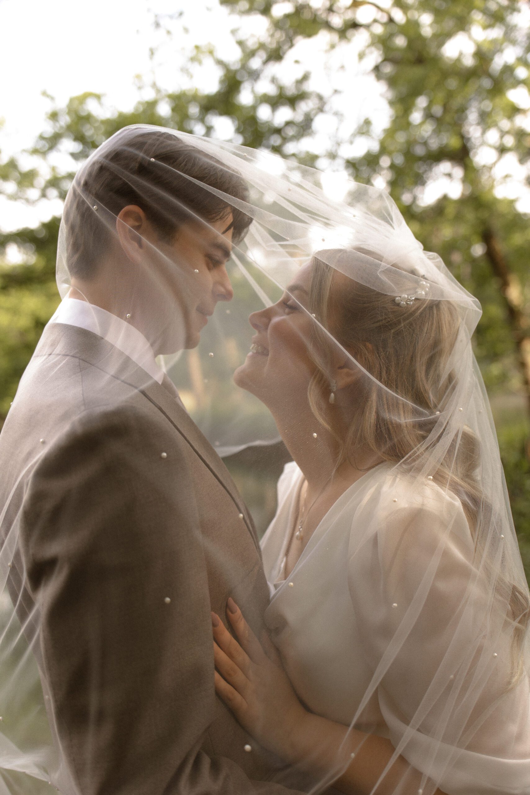 A bride and groom share a moment under a pearled veil near Oude Kerk in Dongen, NL, photographed by Amy Harper Fotografie
